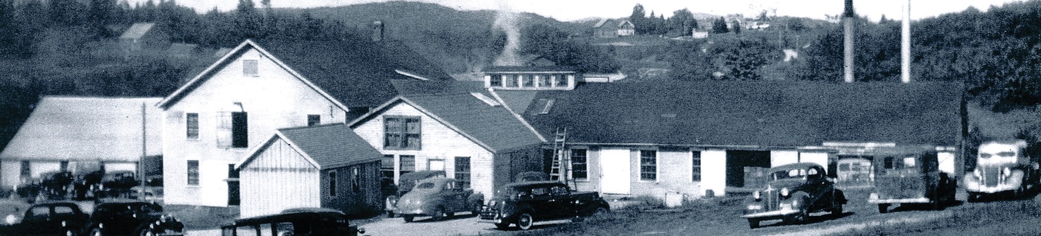 An old photo of a house with cars parked in front of it.