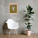 A chair with a plant in front of a wall, adorned by a Shop Wyman's "In Concert with Nature Since 1874" poster.