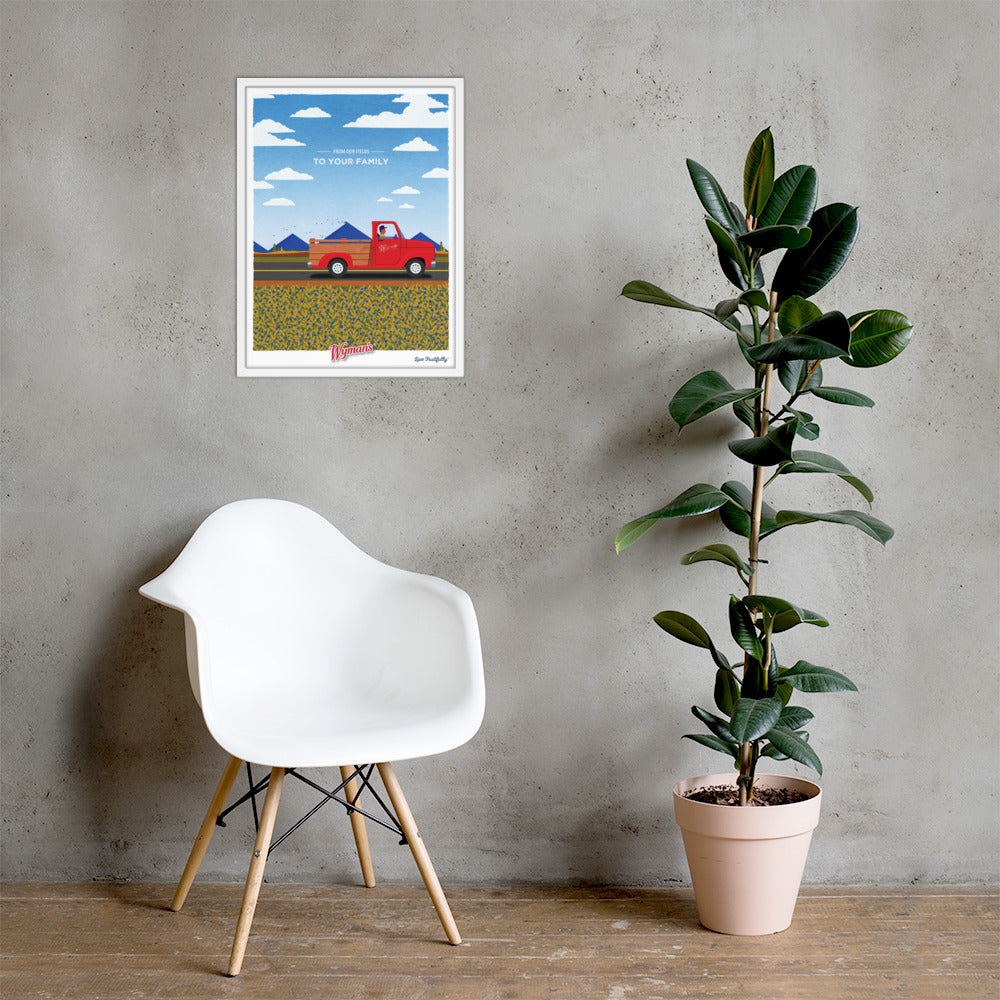 A print of a From Our Fields to Your Family Poster red truck on a wall next to a chair by Shop Wyman's.