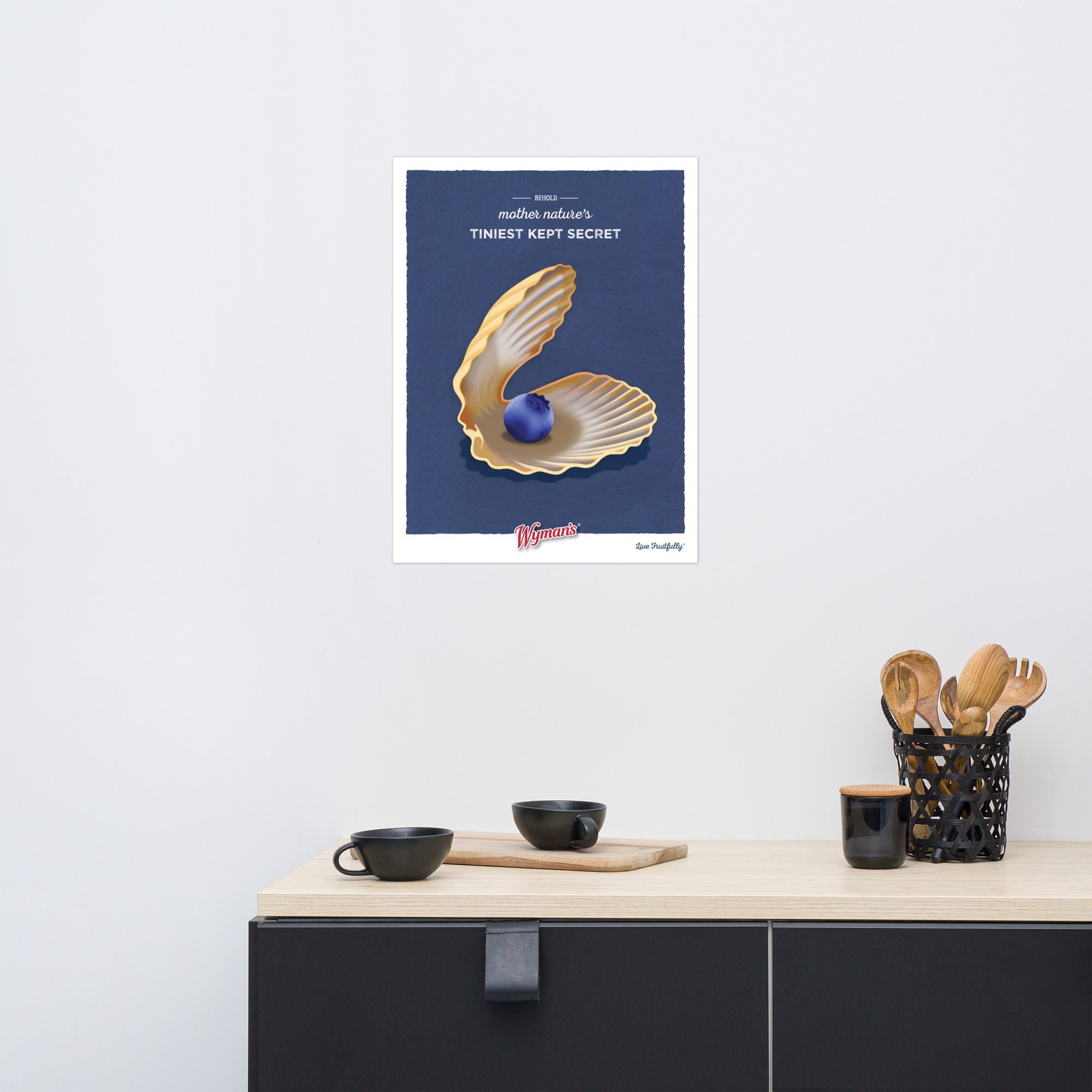 A Behold Mother Nature's Tiniest Kept Secret Poster with an image of a shell, featuring blueberry-themed printing, hanging on a wall from Shop Wyman's.