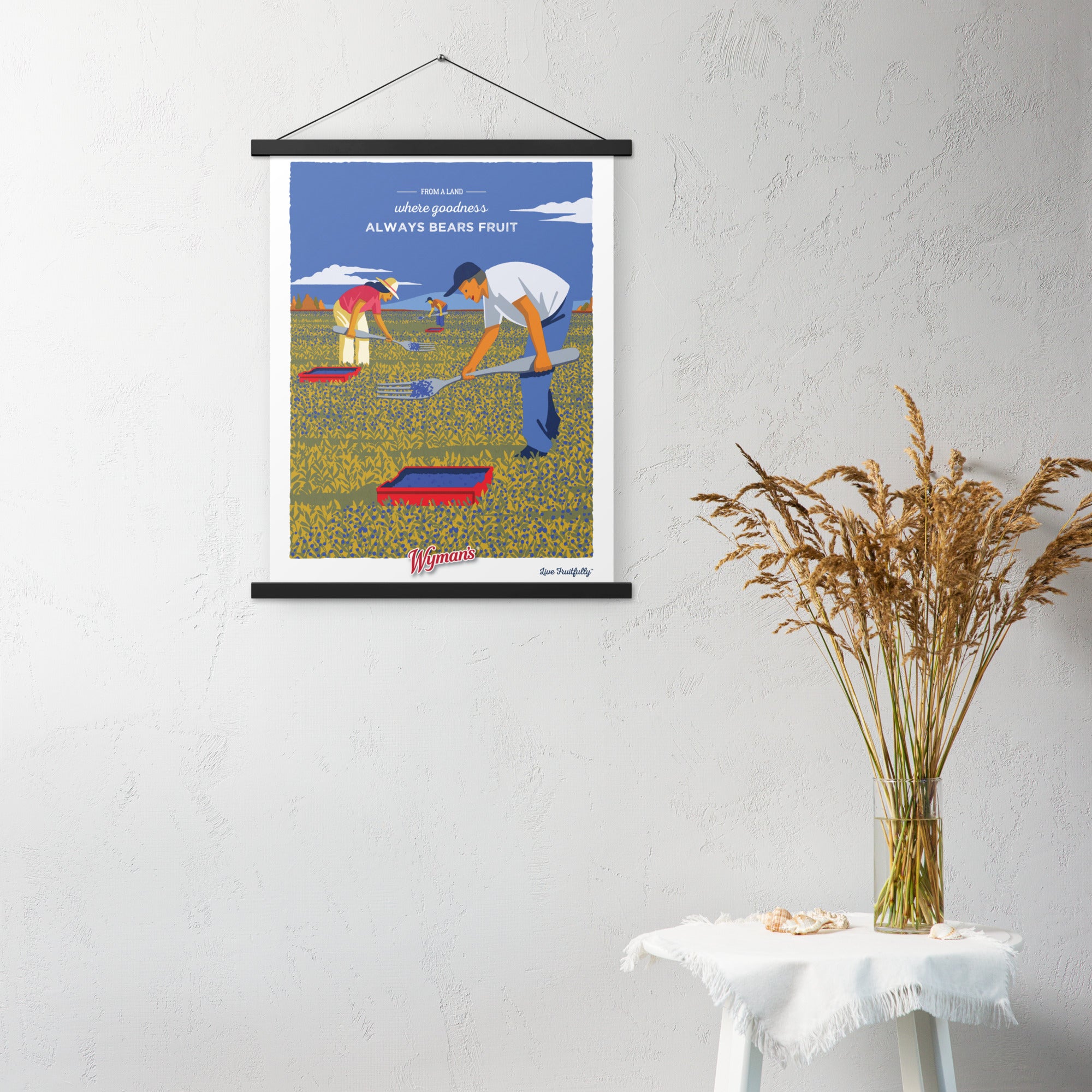 A Shop Wyman's "From a Land Where Goodness Always Bears Fruit" poster with a picture of a man picking blueberries in a field.