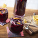 Two glasses of sangria with delicious Whitney Wild Blueberry Juice as one of the ingredients on a wooden table.