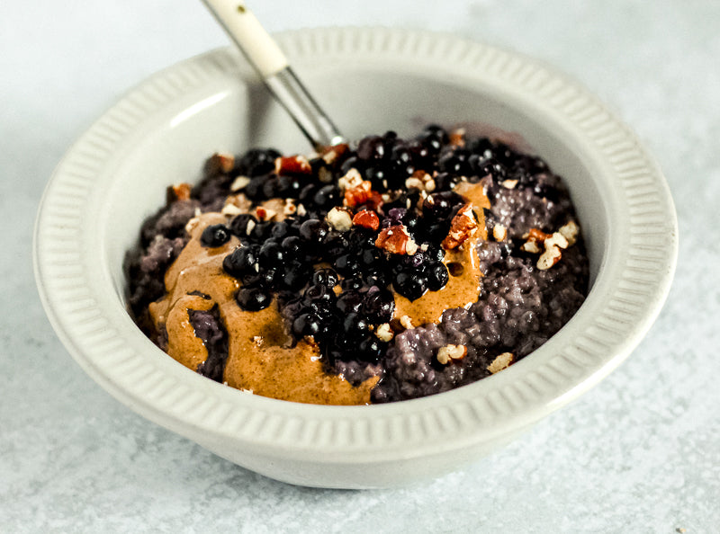 A bowl of oatmeal with Whitney Wild Blueberry Powder and peanut butter.