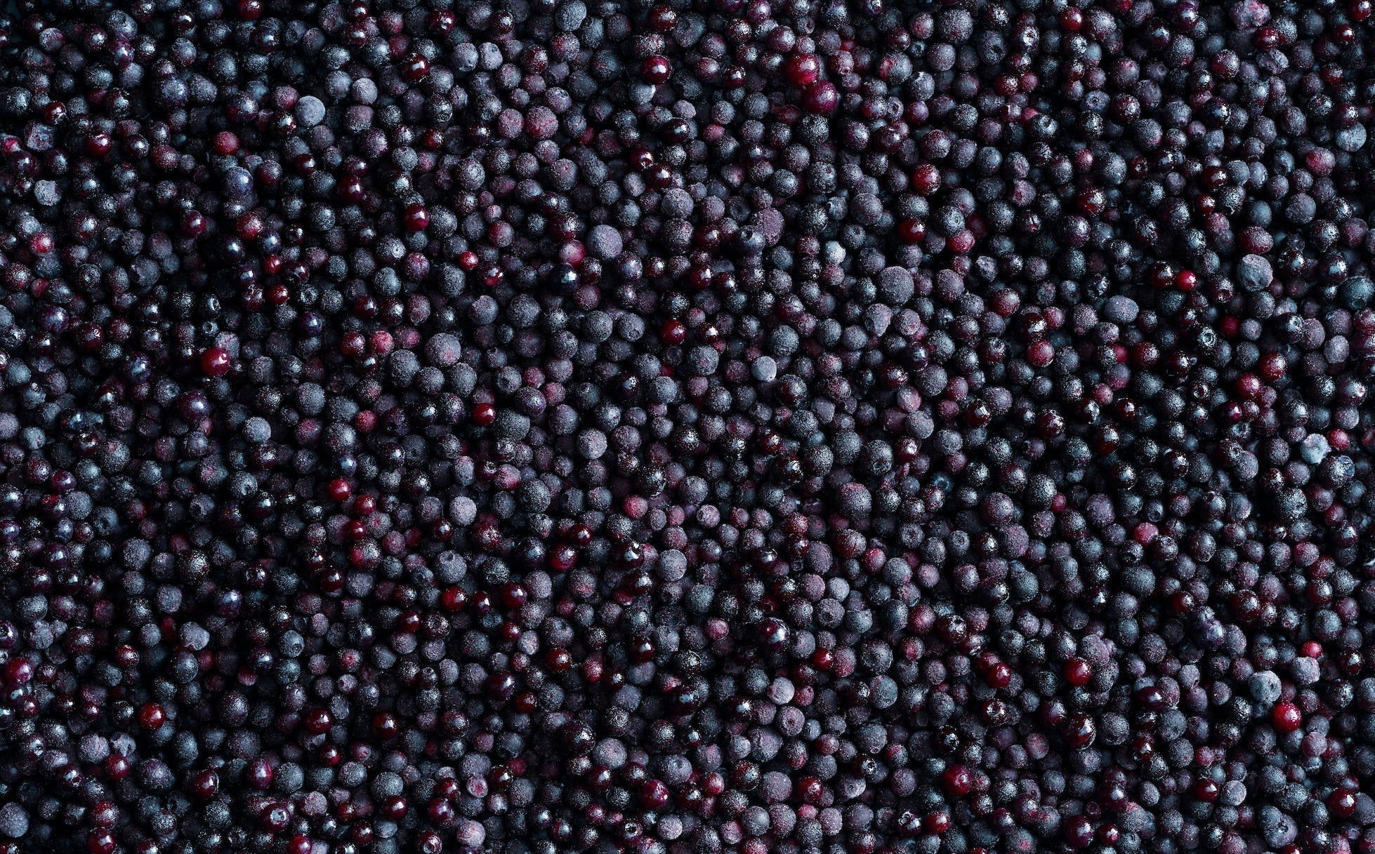 A mix of frozen raspberries, blackberries, and blueberries covers the surface with the text Frozen Fruit overlayed on the left side.