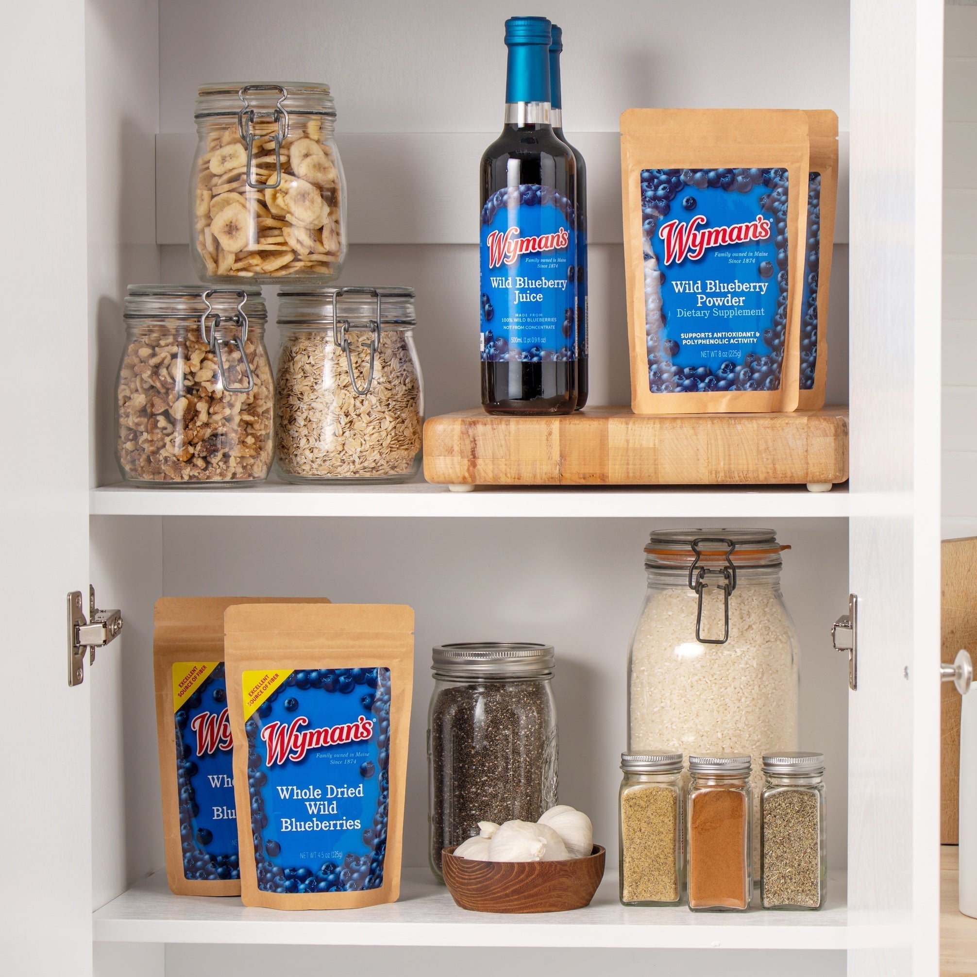 Two shelves with jars and Wymans blueberry products, including dried blueberries, wild blueberry juice, and powder, alongside various pantry staples like grains, pasta, spices, and nuts.