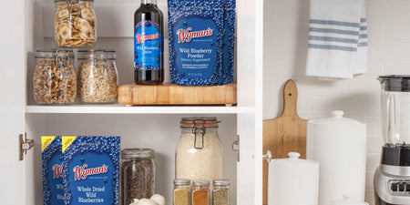 Wymans wild blueberry juice, powder, and dried blueberries arranged on kitchen shelves with glass storage jars.