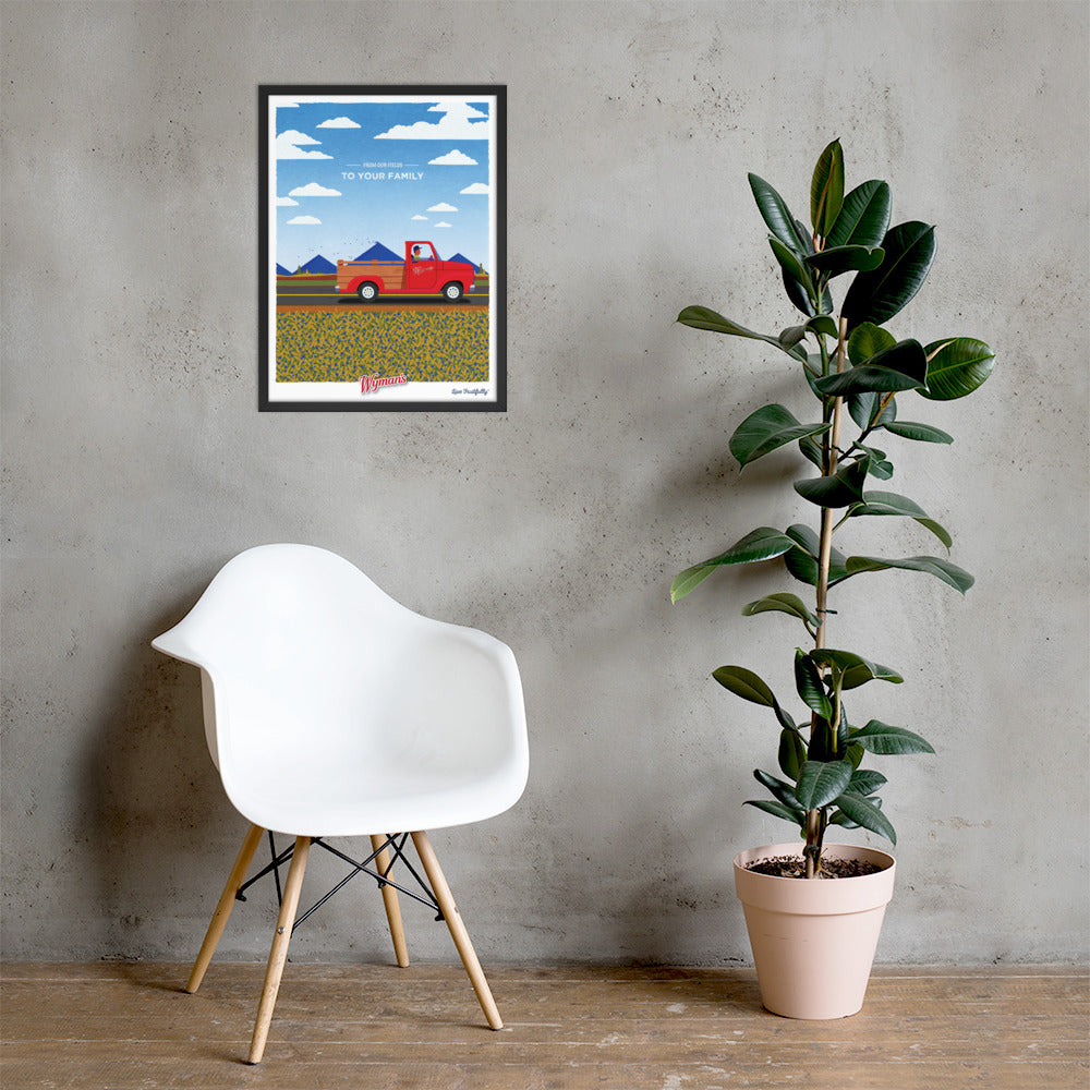 A framed From Our Fields to Your Family Poster of a red truck on a wall next to a chair.