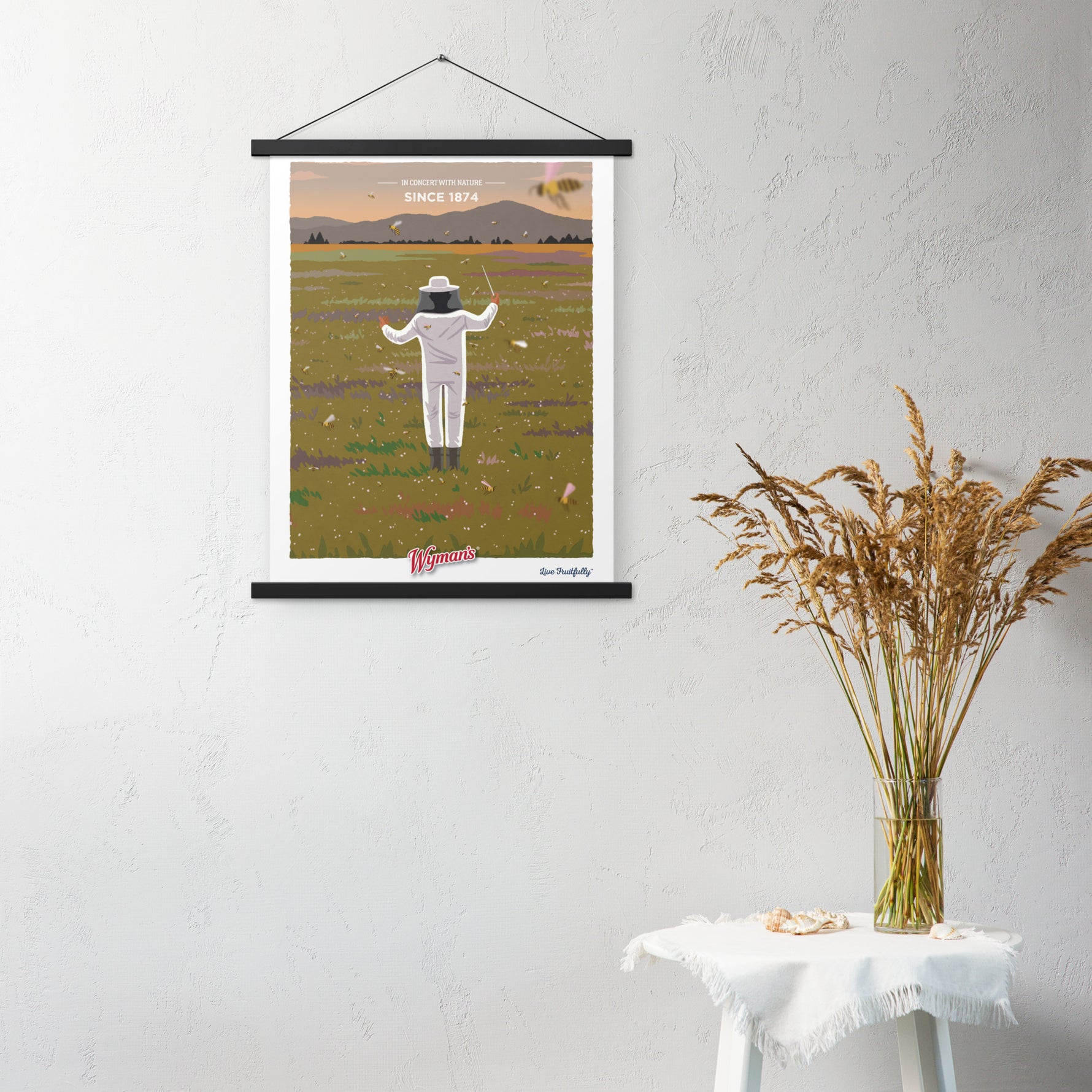A Shop Wyman's "In Concert with Nature Since 1874" poster hanging on a wall with a person standing in the middle of a field.