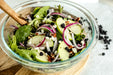 A bowl of salad with apples, onions, and dried Whitney Whole Dried Wild Blueberries - 4.5 oz bag.